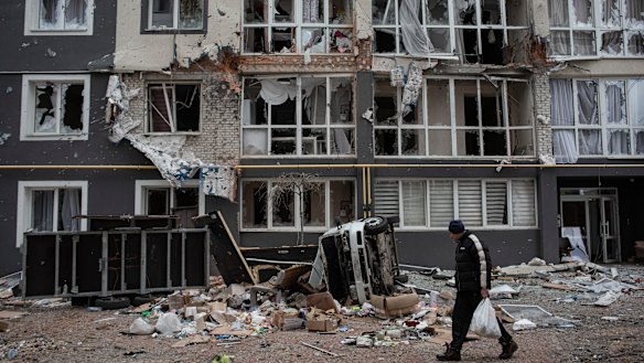 A man walks past a heavily damaged apartment building in Bucha.
