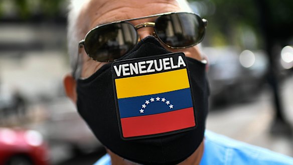 A man wears a face mask with the Venezuela flag, amid the spread of the new coronavirus, as he waits for hours to fill up his car at a state-run oil company PDVSA as station in Caracas.