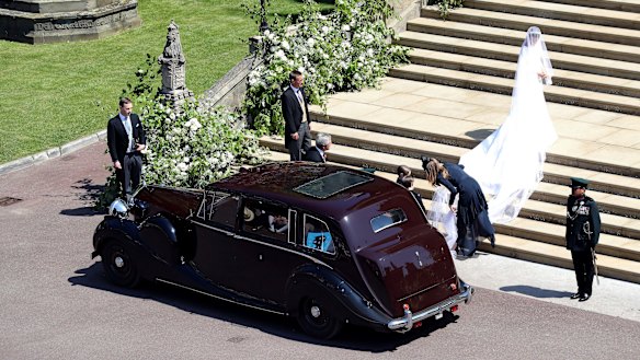 Givenchy designer Clare Waight Keller can be seen adjusting Meghan Markle's wedding dress as she arrives at the chapel for her wedding to Prince Harry.