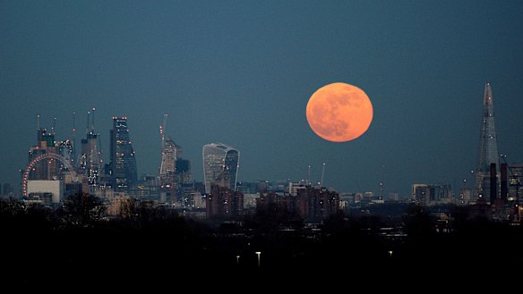 The moon rises over the London skyline.