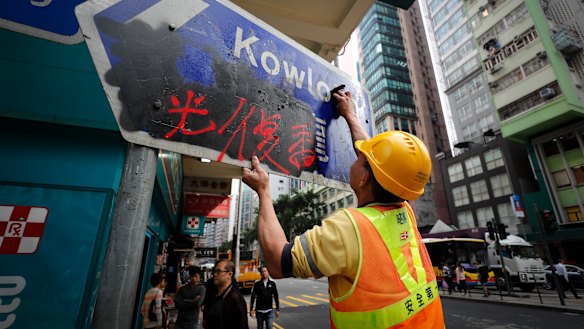 A worker cleans a road sign vandalised by protesters in Causeway Bay, Hong Kong.