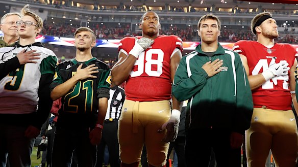 Tribute: San Francisco 49ers defensive end Ronald Blair III (98) and fullback Kyle Juszczyk (44) stand with students from Paradise High School during the national anthem before an NFL football game between the 49ers and the New York Giants in Santa Clara, California, on Monday.