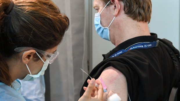 A Qantas pilot receives his vaccination from registered nurse Hedi Soleiman.  