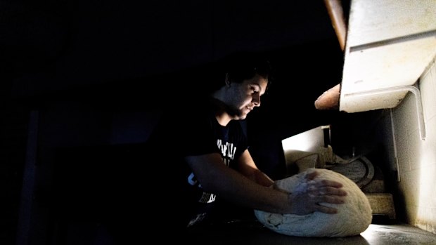 A pizza maker uses battery powered lamps to illuminate his work space during a blackout inside the delivery-only pizza shop in Buenos Aires.