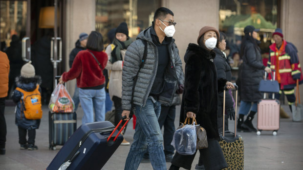 Travellers wear face masks in Beijing as  China reported a sharp rise in the number of people infected with coronavirus.