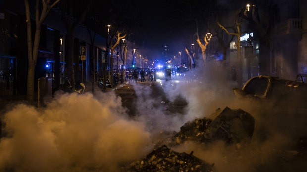 Police officers stand guard near a burning barricade setup by demonstrators at the end of a protest condemning the arrest of rap singer Pablo Hasél in Barcelona, Spain.