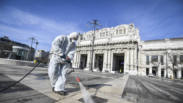 A worker disinfects the area in front of Milan's Centrale railway station.