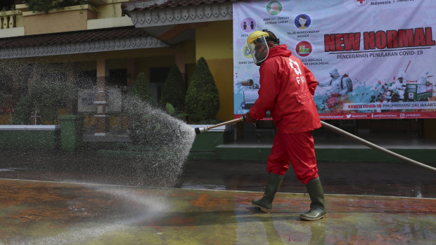 A member of Indonesia Red Cross sprays disinfectant in an attempt to help curb the spread of the coronavirus at a school in Jakarta.