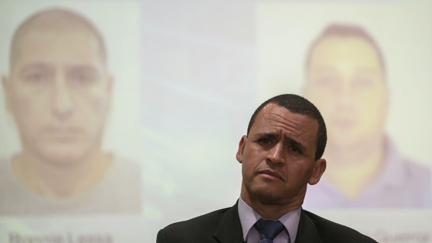Homicide detective Giniton Lajes at the press conference announcing the arrest of two suspects, pictured in the background, in the murder of Marielle Franco and her driver.