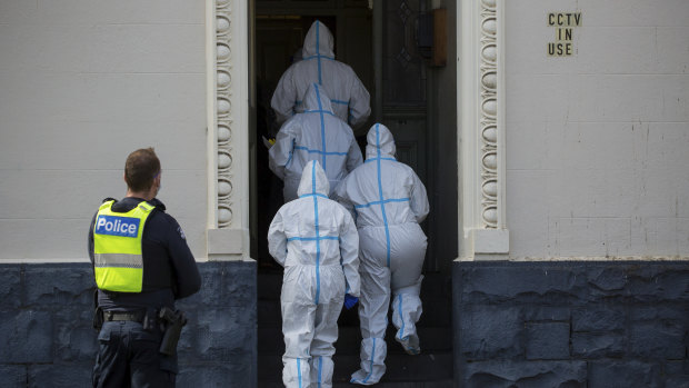 Healthcare workers enter Hambleton House in Albert Park on Sunday morning, after an outbreak and reports of quarantine breaches by residents. 