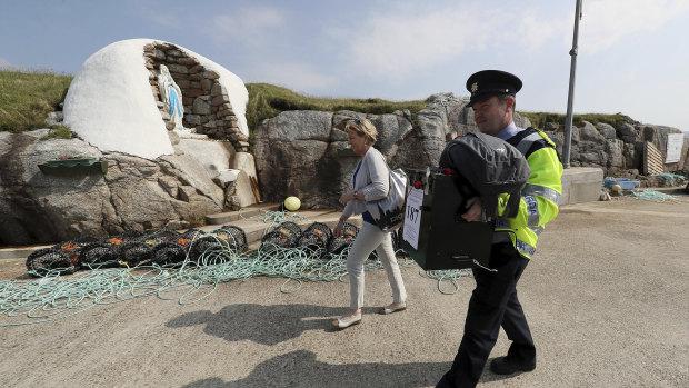 Garda police officer Pat McIlroy and Nancy Sharkey, Presiding Officer for Gola Island, arrive on the island off the coast of Donegal with a ballot box on Thursday.