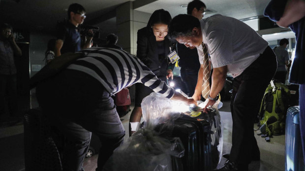 People use torches to check passengers' luggage at a terminal of Asahikawa airport.