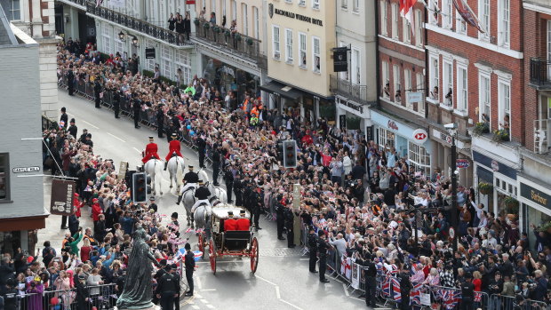 Crowds cheer as the couple leave in a carriage following their wedding ceremony at St George’s Chapel.