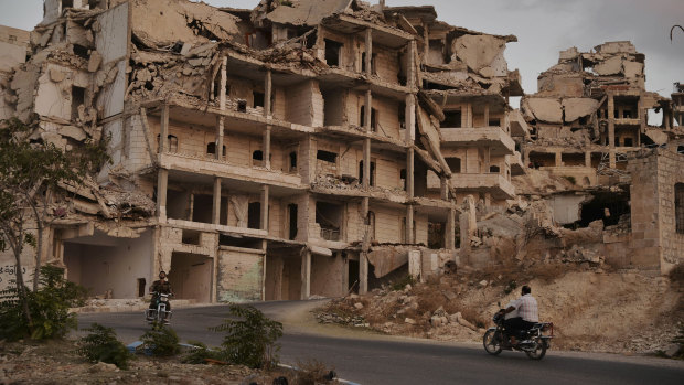 Motor cycles ride past buildings destroyed during the fighting in the northern town of Ariha, in Idlib province, Syria. 
