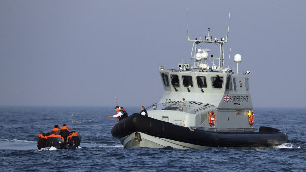 A British Border Force vessel assists a group of people thought to be migrants on board from their inflatable dinghy in the English Channel.