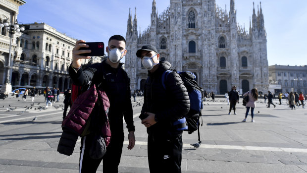 Tourists take a selfie in front of the Duomo gothic cathedral, in Milan, Italy.