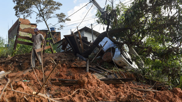 A resident carries a disassembled bed after rescuing it from a landslide-damaged home in Belo Horizonte.
