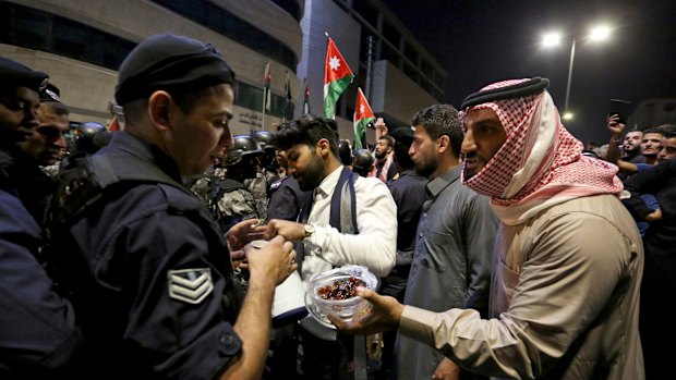 Protesters offer sweets to police officers standing guard in Amman on Tuesday.