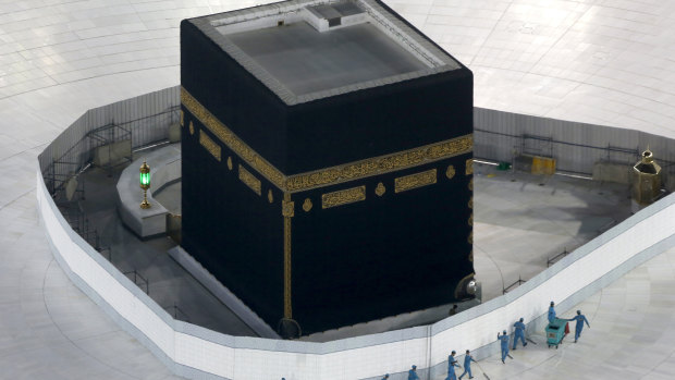 Workers disinfect the ground around the Kaaba, the cubic building at the Grand Mosque, in the Muslim holy city of Mecca, Saudi Arabia. The site is now closed.