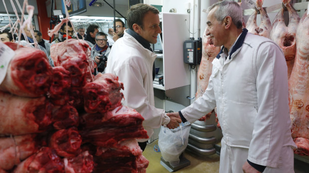 French presidential candidate Emmanuel Macron, left, shakes hands with a butcher as he visits the meat pavillon at the Rungis wholesale food market, south of Paris in May 2017. 