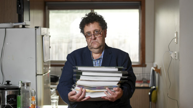 Davidh Digman in his Seaford, Melbourne home, holding his robo-debt files. 