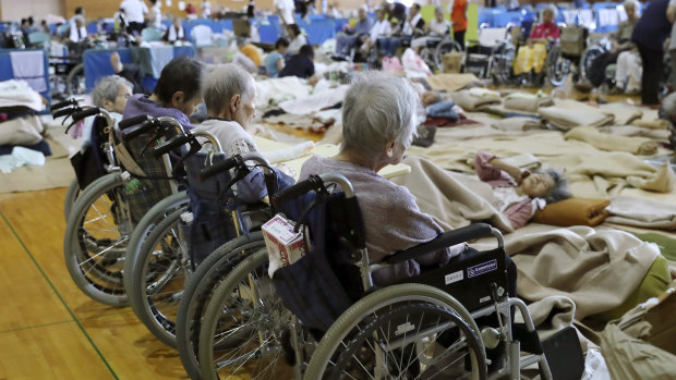 Elderly people from a nursing home take shelter following a heavy rain, in Soja, Okayama prefecture, western Japan on Monday,