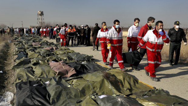 Rescue workers carry the body of a victim of the Ukrainian plane crash to a row of body bags, in Shahedshahr, south-west of Tehran, Iran, on Wednesday.