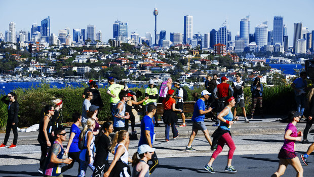Fun-runners battle up Heartbreak Hill as the city shines in the background.
