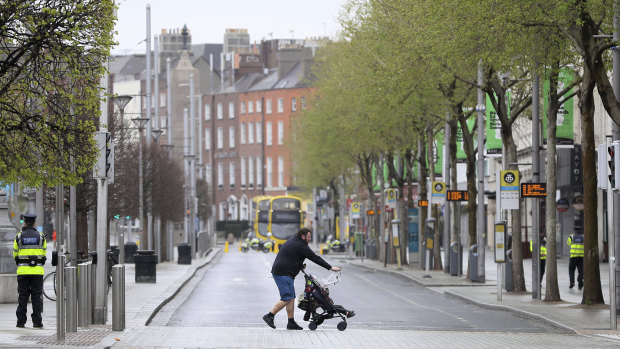 A man pushes a pram across an almost deserted O'Connell Street in Dublin's city centre.