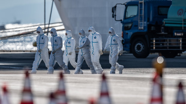 Emergency workers walk from the Diamond Princess cruise ship at Daikoku Pier on Tuesday.