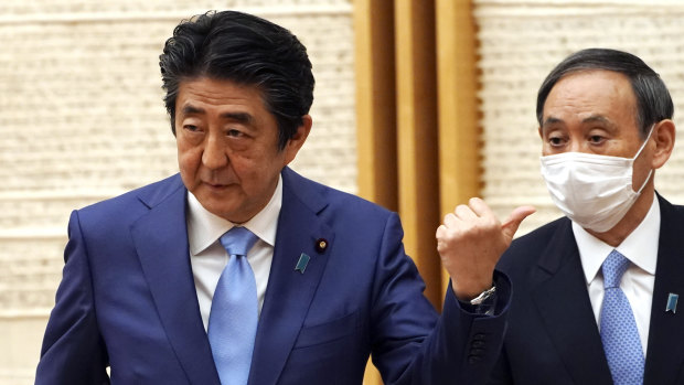 Japan's Prime Minister Shinzo Abe, left, gestures as Chief Cabinet Secretary Yoshihide Suga looks in at the end of a press conference earlier this year.