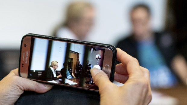 A woman takes a photo of a man in the dock of the court in Freiburg, southern Germany.
