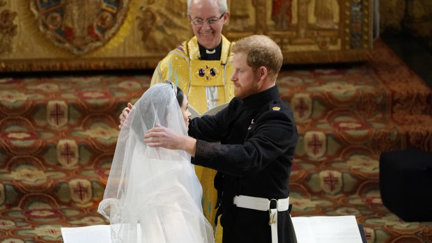  Prince Harry pulls back the veil of Meghan Markle watched by Archbishop of Canterbury Justin Welby during their wedding at St. George's Chapel in Windsor Castle in Windsor.
