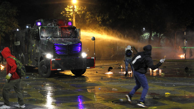 Protesters throw objects to an anti-riot tank as it sprays water during a national strike on May 5 in Medellin, Colombia.