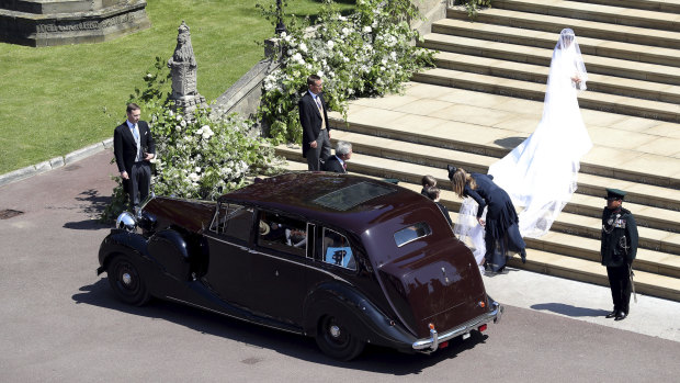 Givenchy designer Clare Waight Keller can be seen adjusting Meghan Markle's wedding dress as she arrives at the chapel for her wedding to Prince Harry.