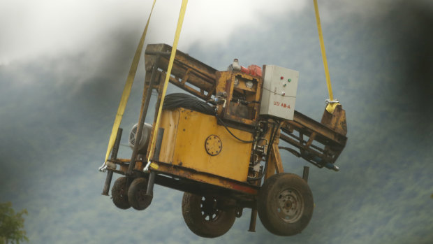 A military transport helicopter carries a drill machine to be used for the rescue search.