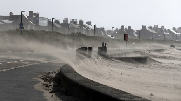 Strong winds whip sand across the seafront road at Troon Beach in Northern Ireland on Wednesday.