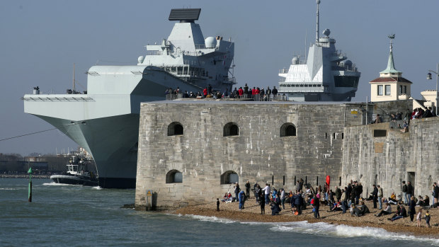 People watch as the Royal Navy aircraft carrier HMS Queen Elizabeth leaves Portsmouth Naval Base, setting sail for exercises at sea, in Portsmouth, England.