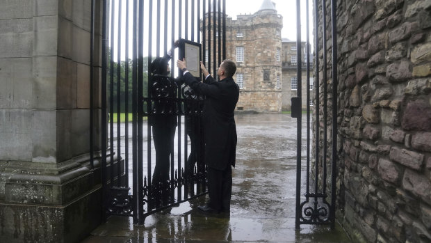 Members of royal household staff post a notice on the gates of the Palace of Holyroodhouse in Edinburgh announcing the death of Queen Elizabeth II.