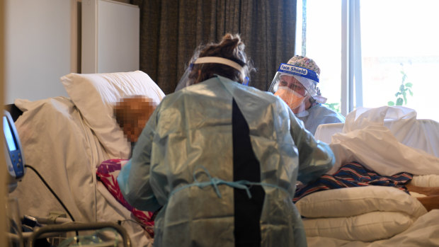 Geriatrician Dr Liz Dapiran and clinical nurse consultant Deanne Lascelles (facing the camera) tend to a patient in a nursing home during the height of an outbreak.