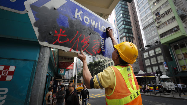 A worker cleans a road sign vandalised by protesters in Causeway Bay, Hong Kong.