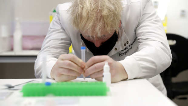 Prime Minister Boris Johnson inspects  a lateral flow test during a visit to a NHS lab in Porton Down.