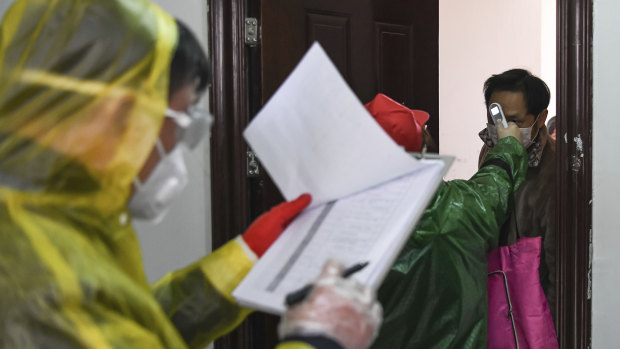 Workers go door to door to check the temperature of residents during a health screening campaign in the Qingshan District of Wuhan.