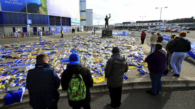 Fans look at the flowers and scarves left outside Cardiff City Stadium in tribute to Sala.