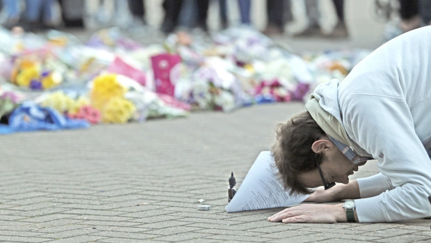 A man prays next to floral tributes outside Leicester City's stadium.