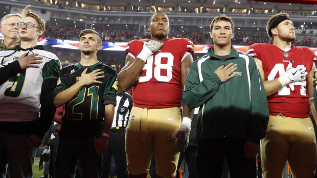 Tribute: San Francisco 49ers defensive end Ronald Blair III (98) and fullback Kyle Juszczyk (44) stand with students from Paradise High School during the national anthem before an NFL football game between the 49ers and the New York Giants in Santa Clara, California, on Monday.