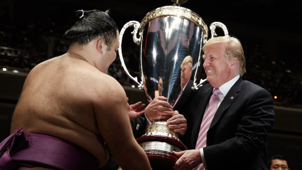 US President Donald Trump presents the President's Cup to the Tokyo Grand Sumo Tournament winner Asanoyama at Ryogoku Kokugikan Stadium in Tokyo.