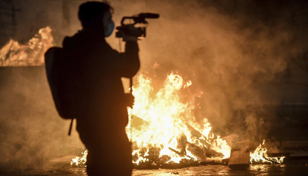 A cameraman films fire after clashes broke out during a protest against the government restriction measures to curb the spread of COVID-19 in Turin, Italy.