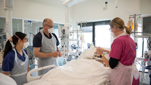 Intensive care director Chris MacIsaac checks a patient with other staff.