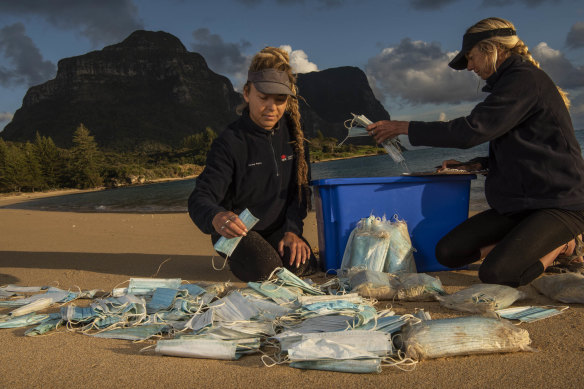 Marine rangers Caitlin Woods and Sallyann Gudge count face masks that have washed up on a Lord Howe Island beach.